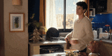 a man in a kitchen with a picture of a pineapple on the wall behind him
