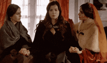 three women are sitting next to each other in a room
