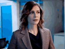 a woman in a suit is standing in a room with a blue wall .