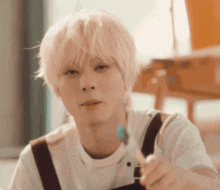 a young man with blonde hair is holding a toothbrush in his hand