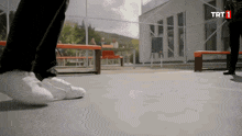 a person 's feet are shown in front of a building that has trt1 on it