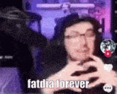 a man with glasses is holding a cell phone and says fatdia forever