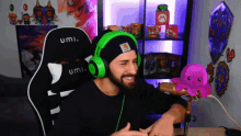a man wearing green headphones and a black beanie sits in an umi chair