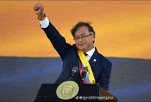 a man stands at a podium with his fist in the air and the words republica de colombia on the podium