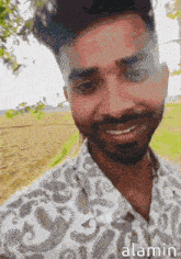 a man with a beard wearing a paisley shirt is smiling for the camera .
