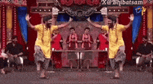 a group of men in yellow shirts are dancing on a stage in front of a crowd .