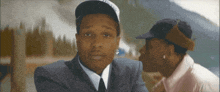 a man in a suit and tie is looking at another man in a baseball cap
