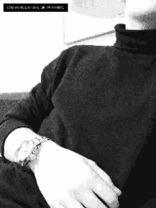 a black and white photo of a man wearing a watch and a turtleneck