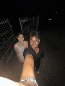a man and a woman pose for a photo in front of a gate
