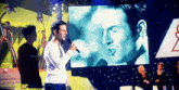 a man is singing into a microphone in front of a large screen that says star academy