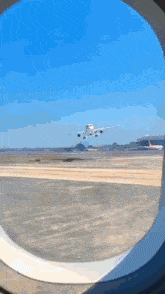 a plane is taking off from an airport runway and is visible through a window