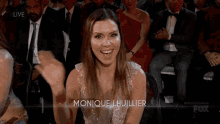 a woman sitting in a crowd with the name monique lhuillier on the bottom