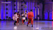 a group of people are dancing on a stage in a room .
