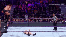 a wrestler is jumping over another wrestler while a referee watches .