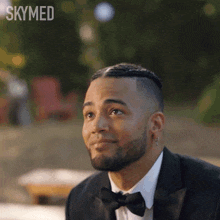 a man in a tuxedo with a bow tie is smiling with skymed written in the corner