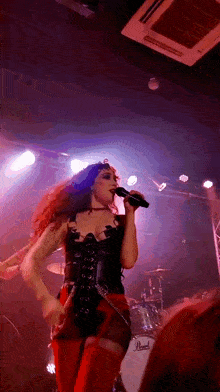 a woman singing into a microphone in front of a drum set that says pearl