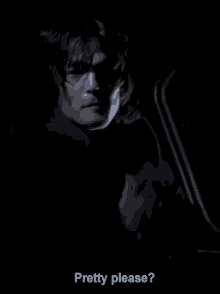 a man in a dark room with the words " pretty please " below him