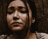 a close up of a woman 's face against a tree
