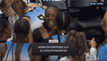 a group of female basketball players are huddled together with a sign that says " wnba enterprises llc all rights reserved "
