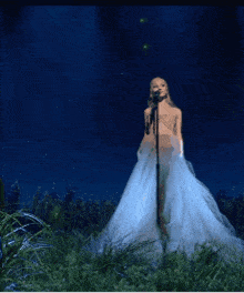 a woman singing into a microphone with a blue background