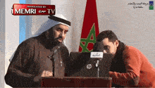 a man stands at a podium with a laptop in front of him and a sign that says " translated by memri tv "