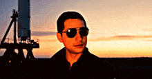 a man wearing sunglasses is standing in front of a rocket