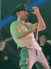 a man in a cowboy hat is singing into a microphone on stage