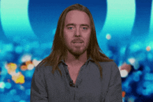 a man with long hair and a beard is wearing a gray shirt
