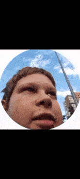 a close up of a boy 's face in a circle with a blue sky in the background