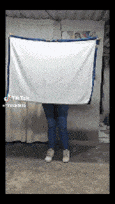 a woman is holding a large white towel behind her back .