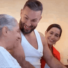 a man with a beard is hugging an elderly woman while two women smile .