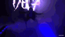 a woman is flying through the air in front of a large screen with a picture of a woman on it .