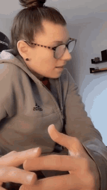 a woman wearing glasses and a hoodie with the word adidas on the front