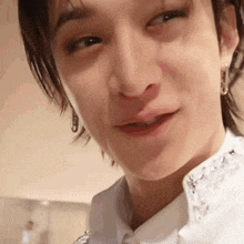 a close up of a man wearing earrings and a white shirt making a funny face .