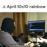 a person wearing a mask is typing on a keyboard in front of a computer monitor ..c april 10x10 rainbow