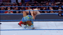 a woman is wrestling another woman in a wrestling ring with a crowd watching .