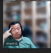 a man wearing headphones and a green shirt is on a video call with a name tag that says hanh d.