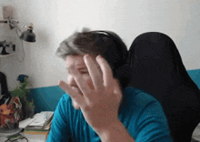 a man in a blue shirt is wearing headphones and making a face