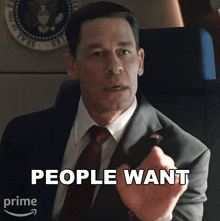 a man in a suit and tie is pointing at the camera and says people want