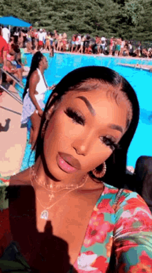 a woman is taking a selfie in front of a swimming pool with a crowd of people .