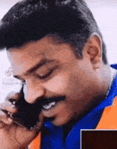 a man is talking on a cell phone and smiling .