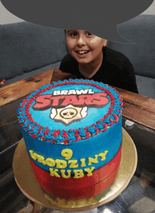 a boy looks at a brawl stars cake on a table