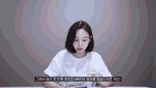 a woman in a white shirt is sitting at a table with korean writing on the bottom