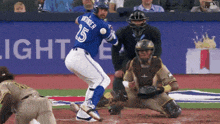 a baseball player with the number 15 on his back swings at a pitch