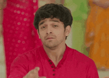 a man in a red shirt is making a funny face and making a funny face .
