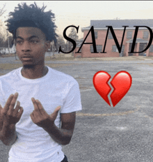 a man in a white shirt stands in front of a broken heart with the word sand written above him