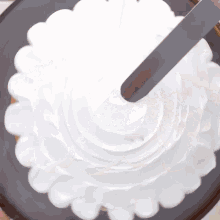 white frosting is being spread on top of a black cake