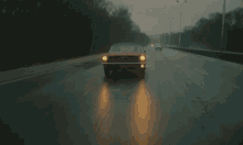 a red ford mustang is driving on a wet road