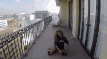 a woman is sitting on the floor on a balcony wearing a shirt that says all