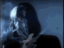 a man in a suit is playing a guitar in a dark room with a blue background .